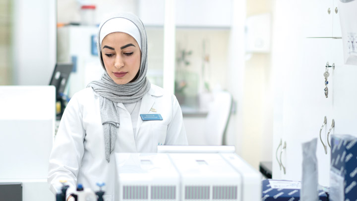 A woman wearing a head scarf and a lab coat in a lab
