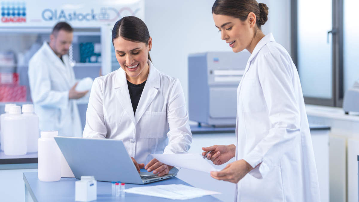 OEM, two females discussing at a laptop in the lab