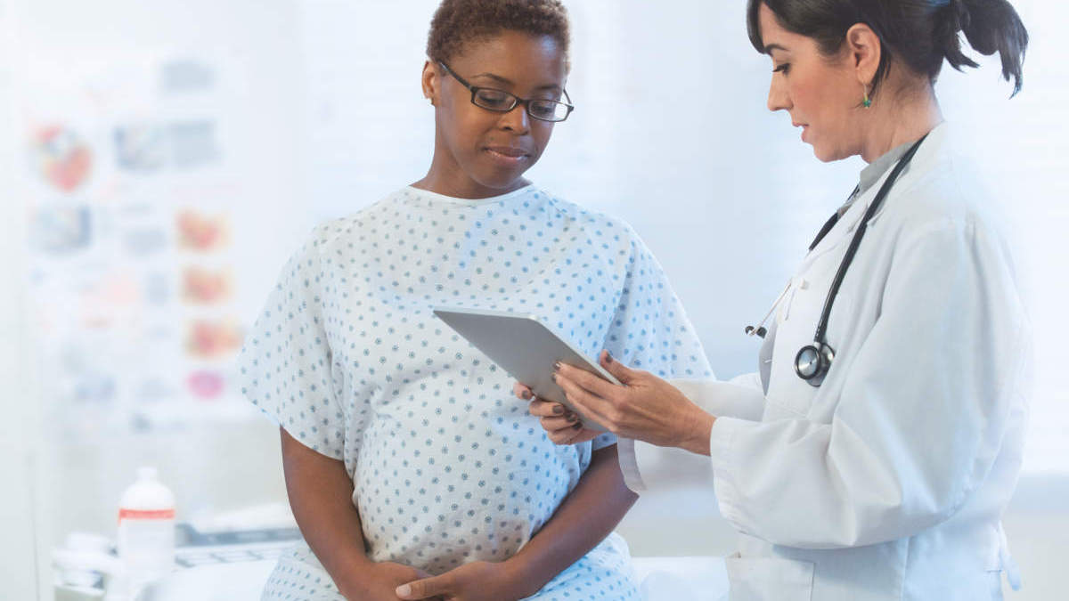 Female doctor and pregnant female patient using digital tablet in hospital