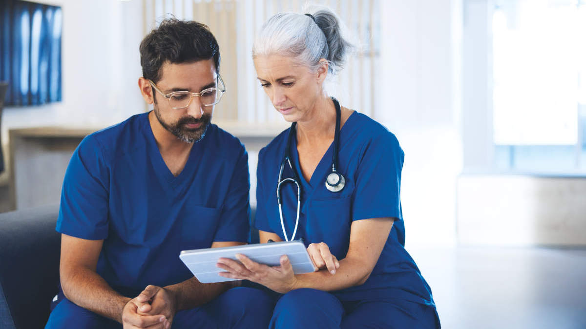 female older doctor discussing results on a tablet with a male health care worker